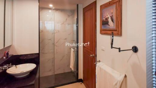 Modern bathroom with glass shower, wooden door, and wall-mounted sink