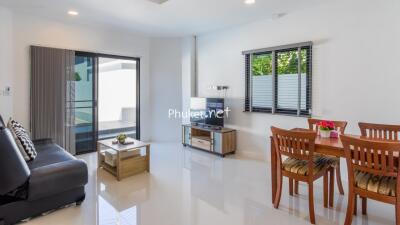 Modern living room with sofa, coffee table, TV, and dining area