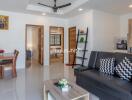 Modern living room with black sofa, decorative pillows, dining table, and ceiling fan