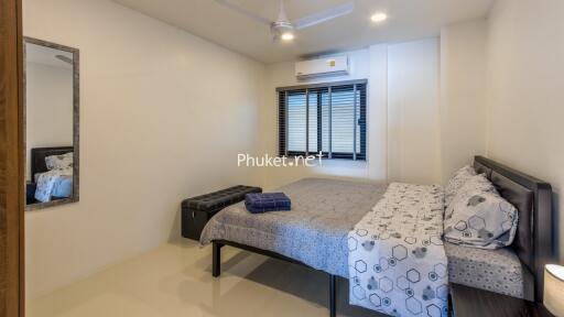 Modern bedroom with a bed, window blinds, AC, ceiling fan, mirror, and side table.