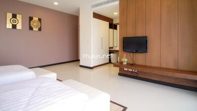 Modern bedroom with two single beds, wall-mounted TV, and built-in closet