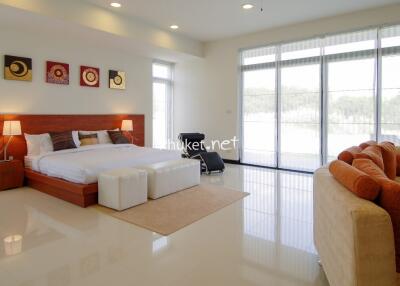 Spacious bedroom with large bed, seating area, and large windows