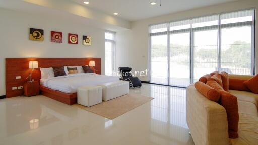 Spacious bedroom with large bed, seating area, and large windows