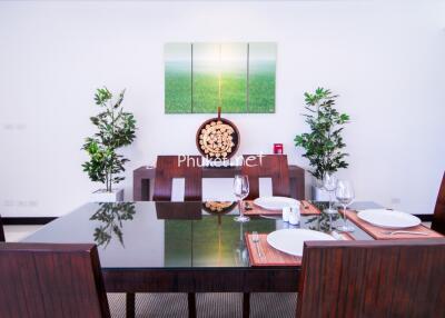 Modern dining room with wooden table and chairs, decorated with paintings and plants