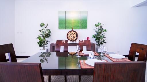 Modern dining room with wooden table and chairs, decorated with paintings and plants