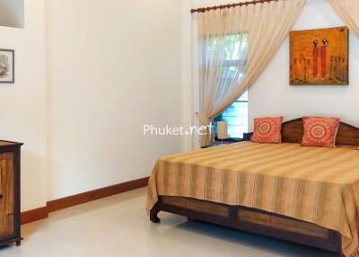 Cozy bedroom with a large bed, wooden furniture, and decorative elements.