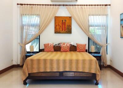 Bedroom with a large bed, draped curtains, and decorative artwork