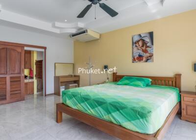 Spacious bedroom with a large bed, wooden furniture, and modern amenities