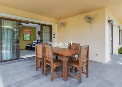 Outdoor patio area with wooden dining set and view of indoor living space