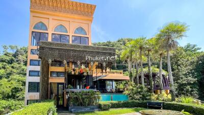 Exterior view of a multi-story building with a garden and pool