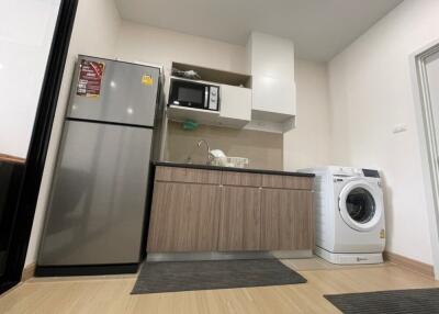 Compact kitchen with modern appliances, including a refrigerator, microwave, and washing machine