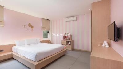 Modern bedroom with striped accent wall, bed, wall-mounted TV, and air conditioning