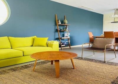 Modern living room with a bright yellow sofa, wooden coffee table, and dining area