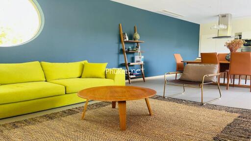 Modern living room with a bright yellow sofa, wooden coffee table, and dining area