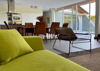 Modern living room with green couch, dining area, and large windows