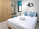 Modern bedroom with wooden wardrobe, large bed, decorative cushions, and wall art