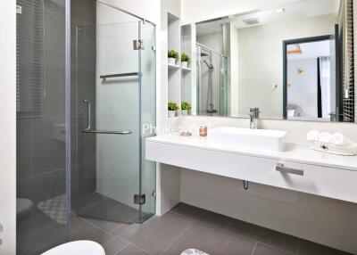 Modern bathroom with glass shower enclosure, sink, mirror, and shelving.