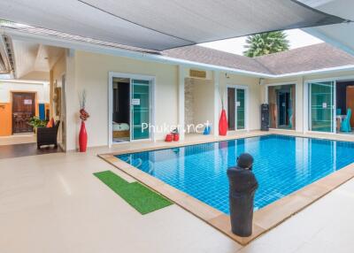 Modern indoor swimming pool area with lounge chairs and decoration