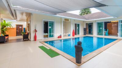 Modern indoor swimming pool area with lounge chairs and decoration