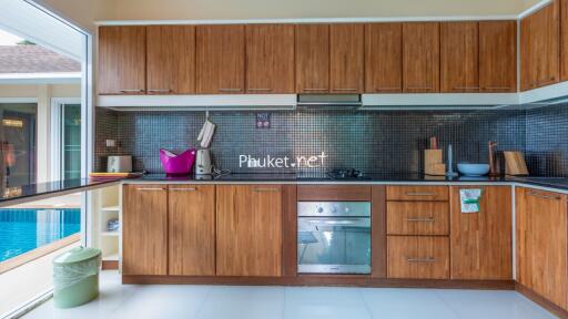 Modern kitchen with wooden cabinets, built-in appliances, and pool view