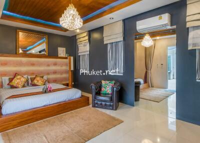 Luxurious bedroom with modern decor featuring a large bed, elegant chandelier, and comfortable seating