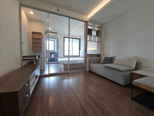 Modern living area with glass partition leading to bedroom