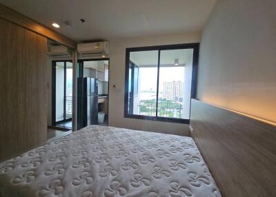 Modern bedroom with white mattress, wooden headboard, balcony view, and large sliding mirror door