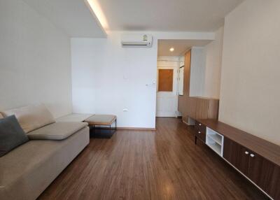 Modern living room with wooden floor, sectional sofa, and entertainment unit