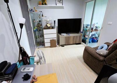 Cozy living room with a TV, shelves, and a comfortable chair.