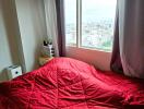 Bedroom with a large window and red quilt