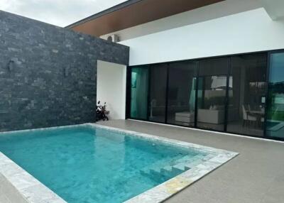 Modern outdoor pool area with glass doors leading to indoor living spaces