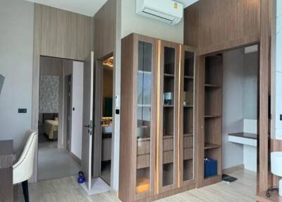 Modern bedroom with built-in wooden shelving and access to bathroom