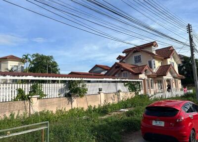 Exterior view of a residential house with red roof tiles and a large fence