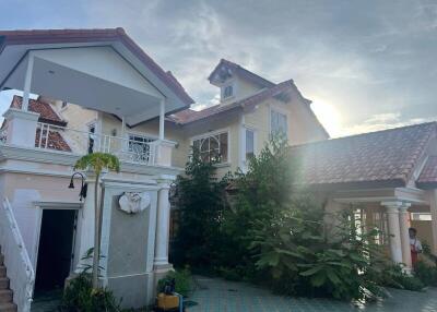 Front view of a large house with a tiled roof and landscaped garden