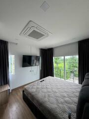 Modern bedroom with a large bed, wall-mounted TV, and balcony access.