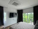 Modern bedroom with a large bed, wall-mounted TV, and balcony access.