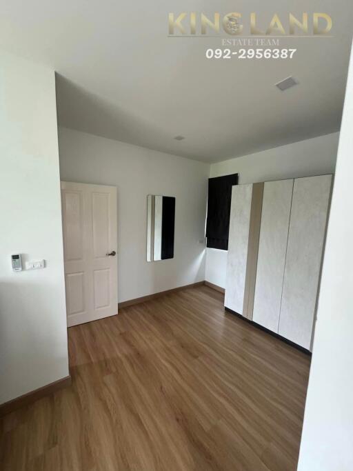 Bedroom with wooden floor, a door, a mirror on the wall, a window, and a wardrobe