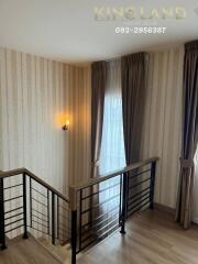 stairwell with wooden railings and elegant wallpaper