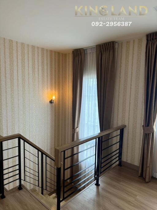 stairwell with wooden railings and elegant wallpaper