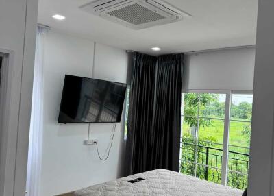 Bedroom with bed, mounted TV, large window with curtains, and air conditioning