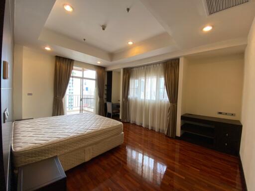 Spacious bedroom with wooden floor and large windows