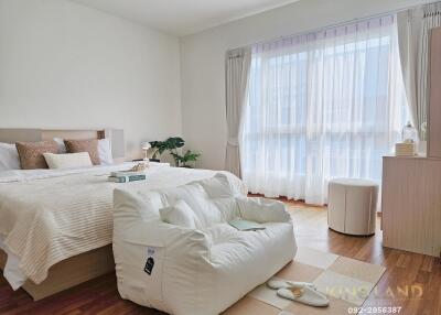 Spacious and bright bedroom with a large window, bed, and cozy seating area