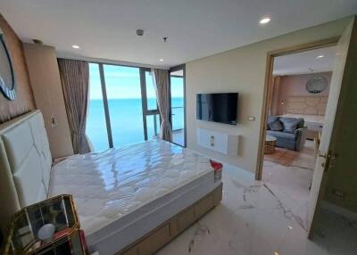 Bedroom with a large window view of the ocean and an adjacent living room