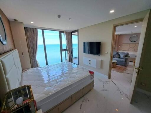 Bedroom with a large window view of the ocean and an adjacent living room