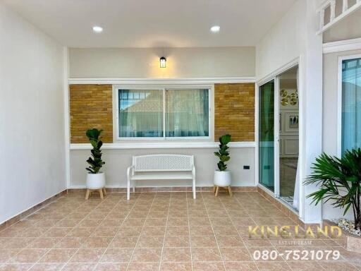 Spacious living area with tiled flooring, a white bench, two potted plants, and a large window