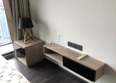 Modern bedroom with a side table, lamp, and mounted shelf