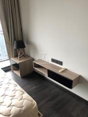 Modern bedroom with a side table, lamp, and mounted shelf