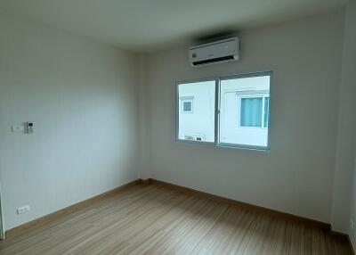 Spacious empty bedroom with wooden floor and air conditioning