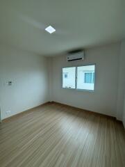 Spacious empty bedroom with wooden floor and air conditioning