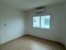 Spacious empty bedroom with wooden floor and air conditioning